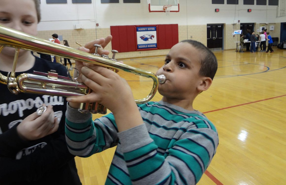 A boy at and education program trying out the trumpet.