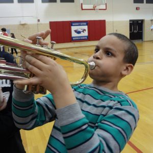 A boy at and education program trying out the trumpet.