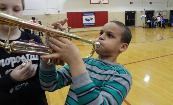 A boy at and education program trying out the trumpet.